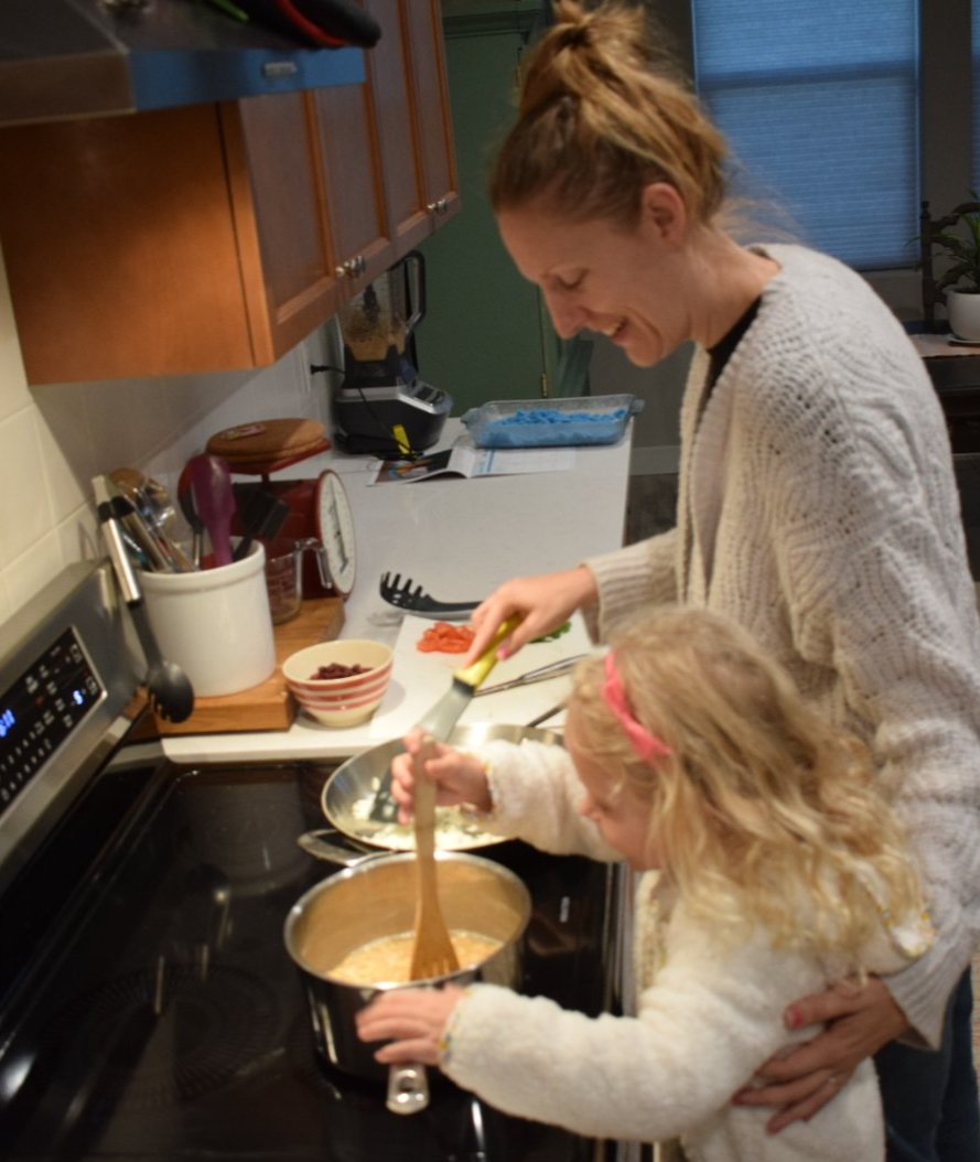 Lauren cooking at a stove with a young child