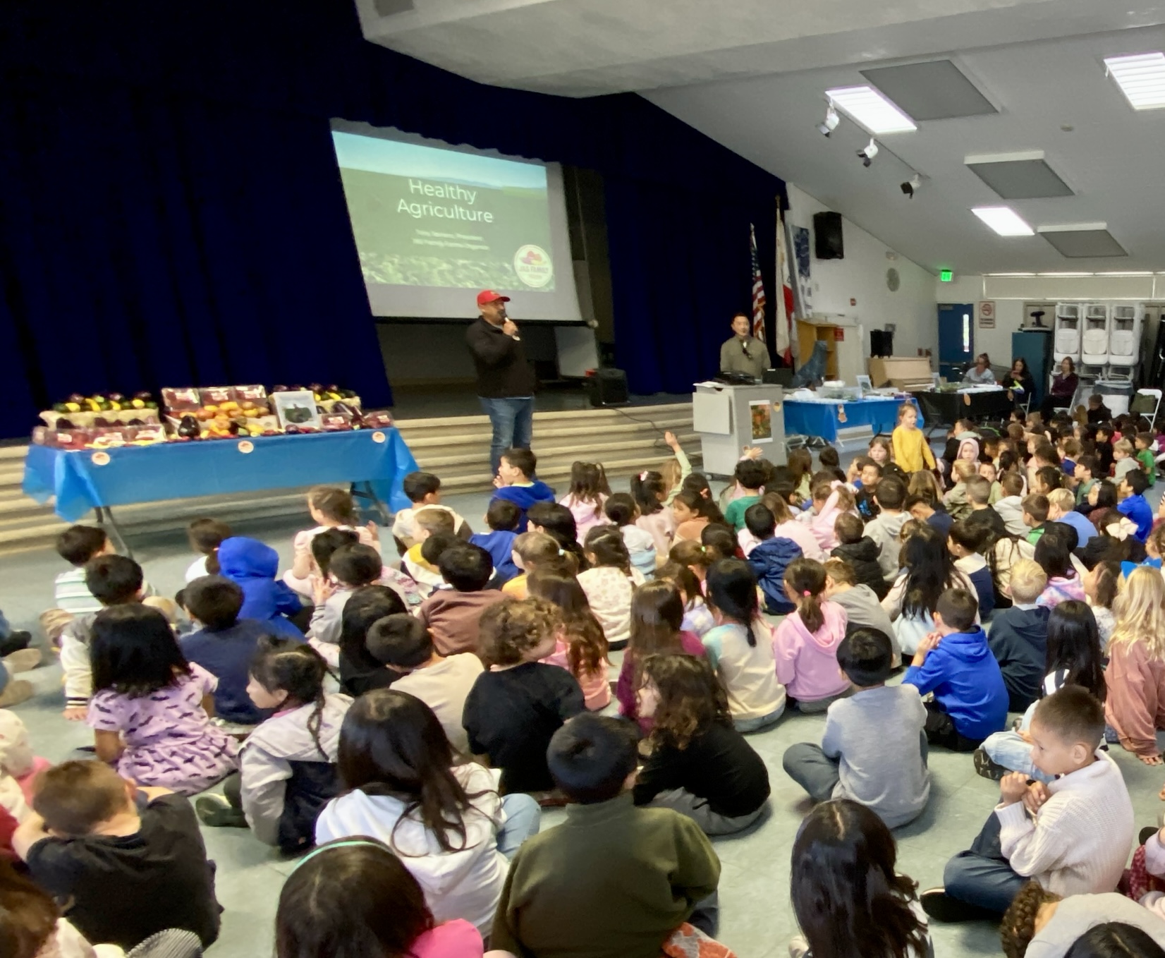Farmer Tony stands in front of seated children at a school assembly