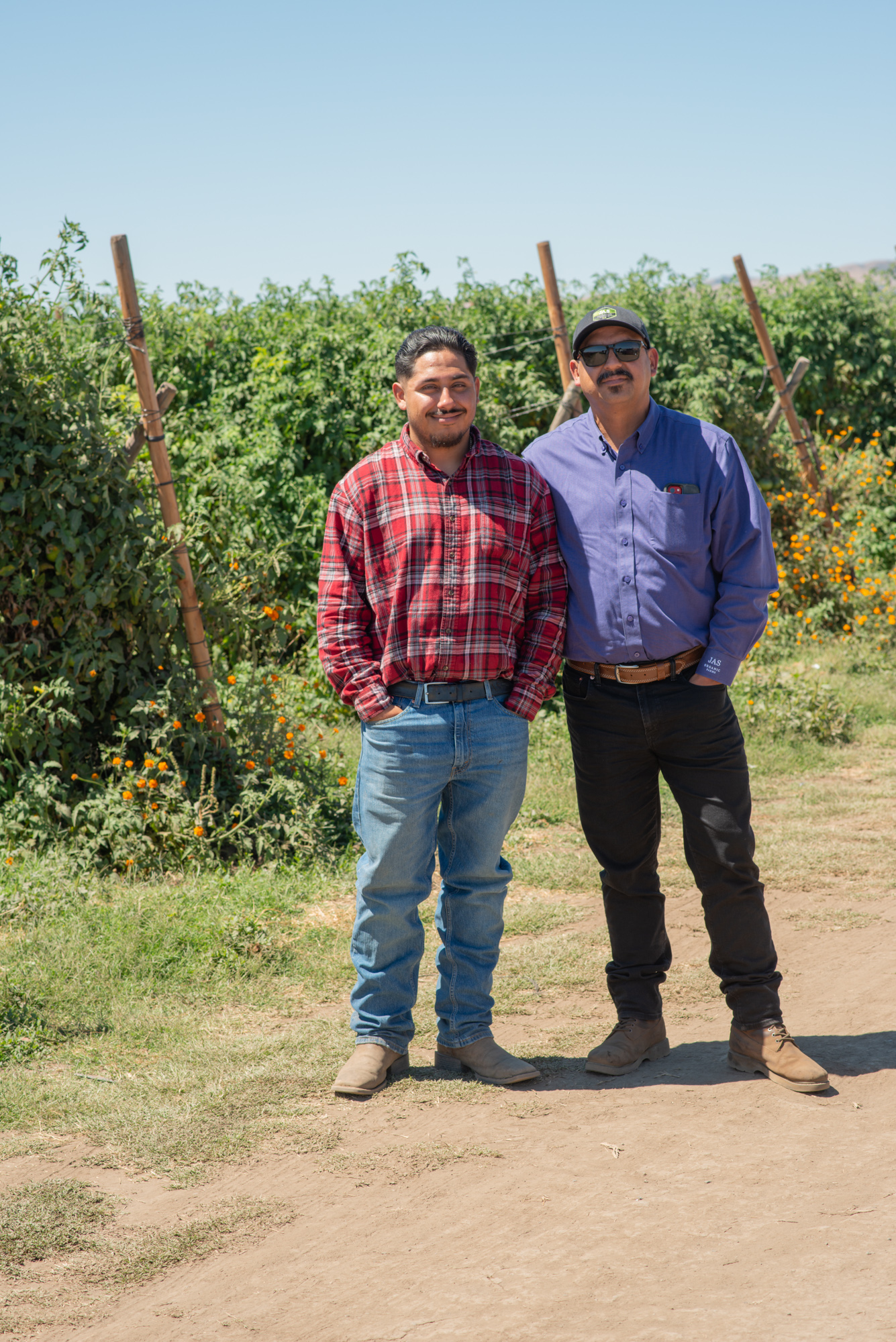 Farmer Tony and his son stand on a dirt path in a field