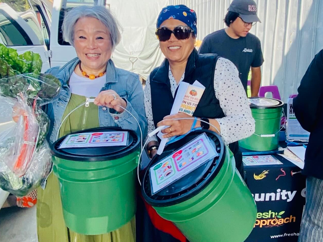 Two people holding compost buckets at the farmers market