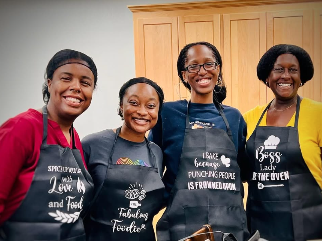 Four people in aprons leading a healthy cooking class