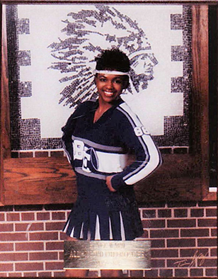 Woman poses in cheerleading uniform.