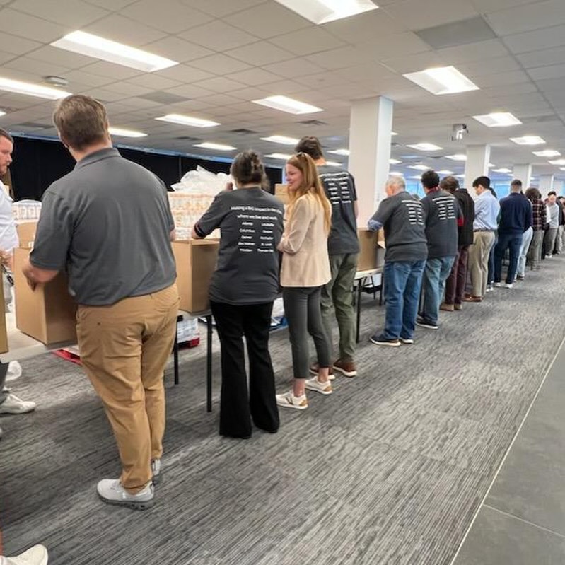 Assembly line of volunteers packing food boxes