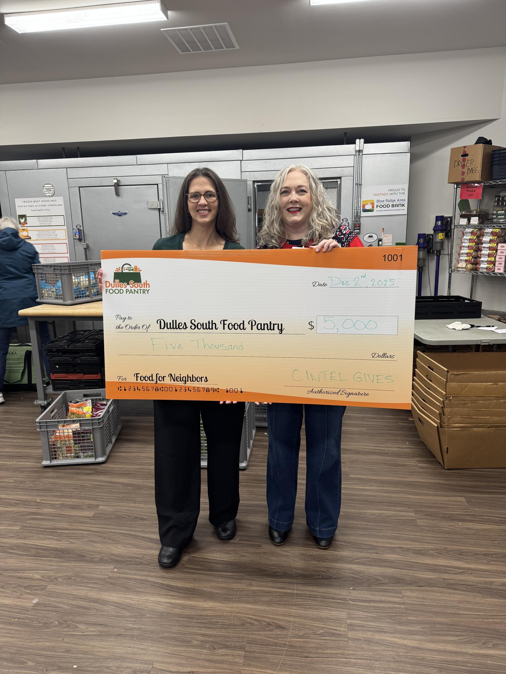 Two people holding a ceremonial check in front of Pantry freezer