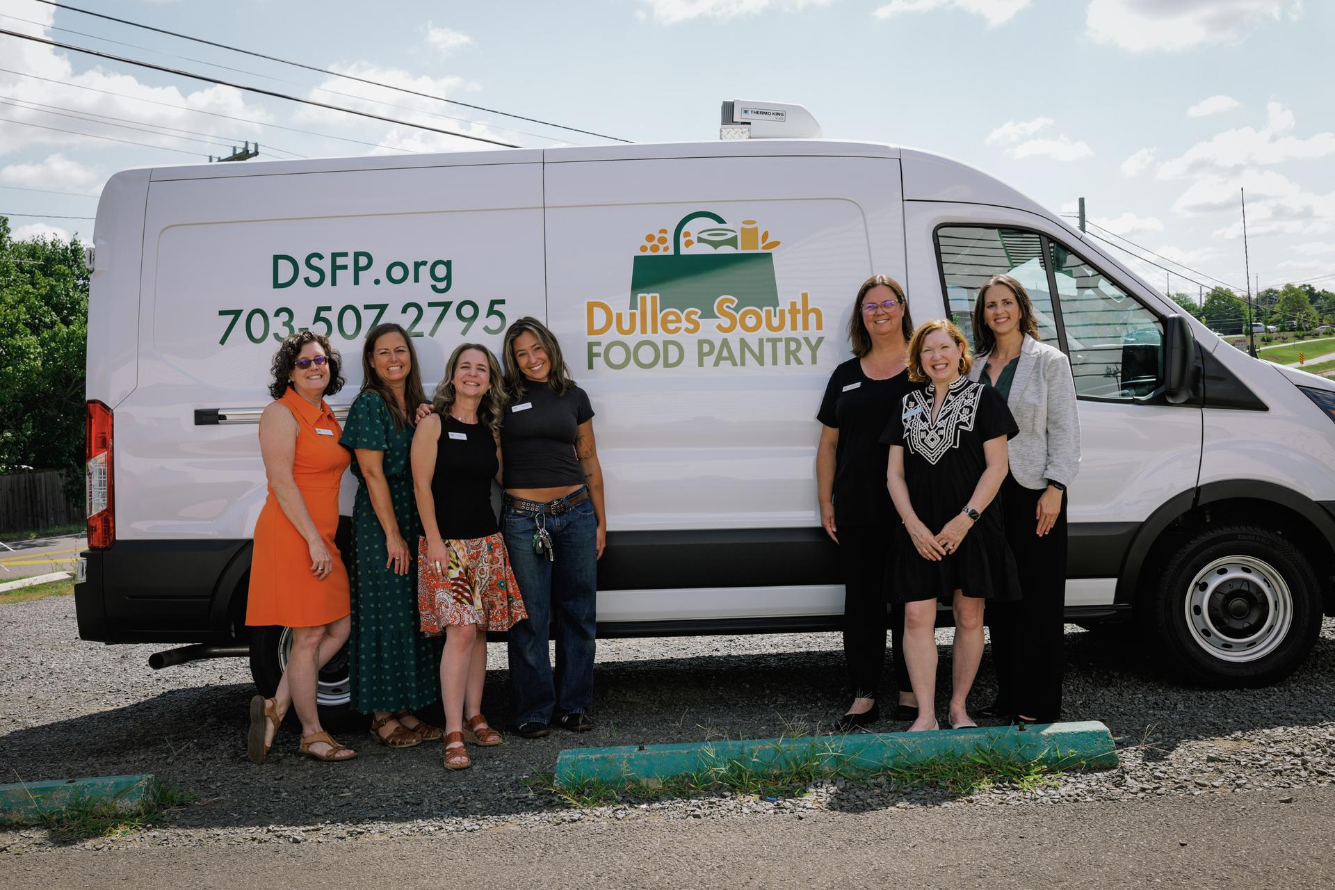 DSFP staff standing together outside in front of the white cargo van with the DSFP logo