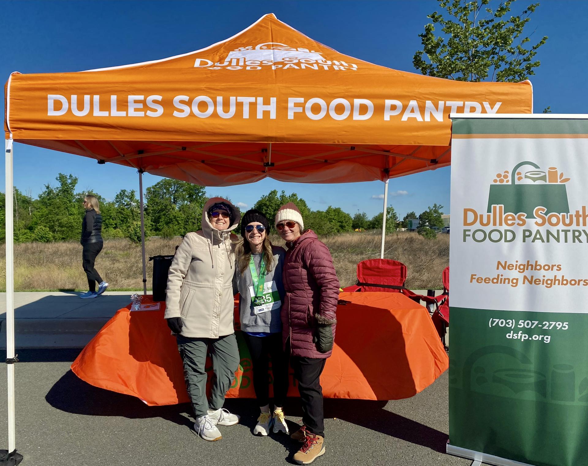 DSFP staff standing under an orange outdoor tent next to a DSFP sign