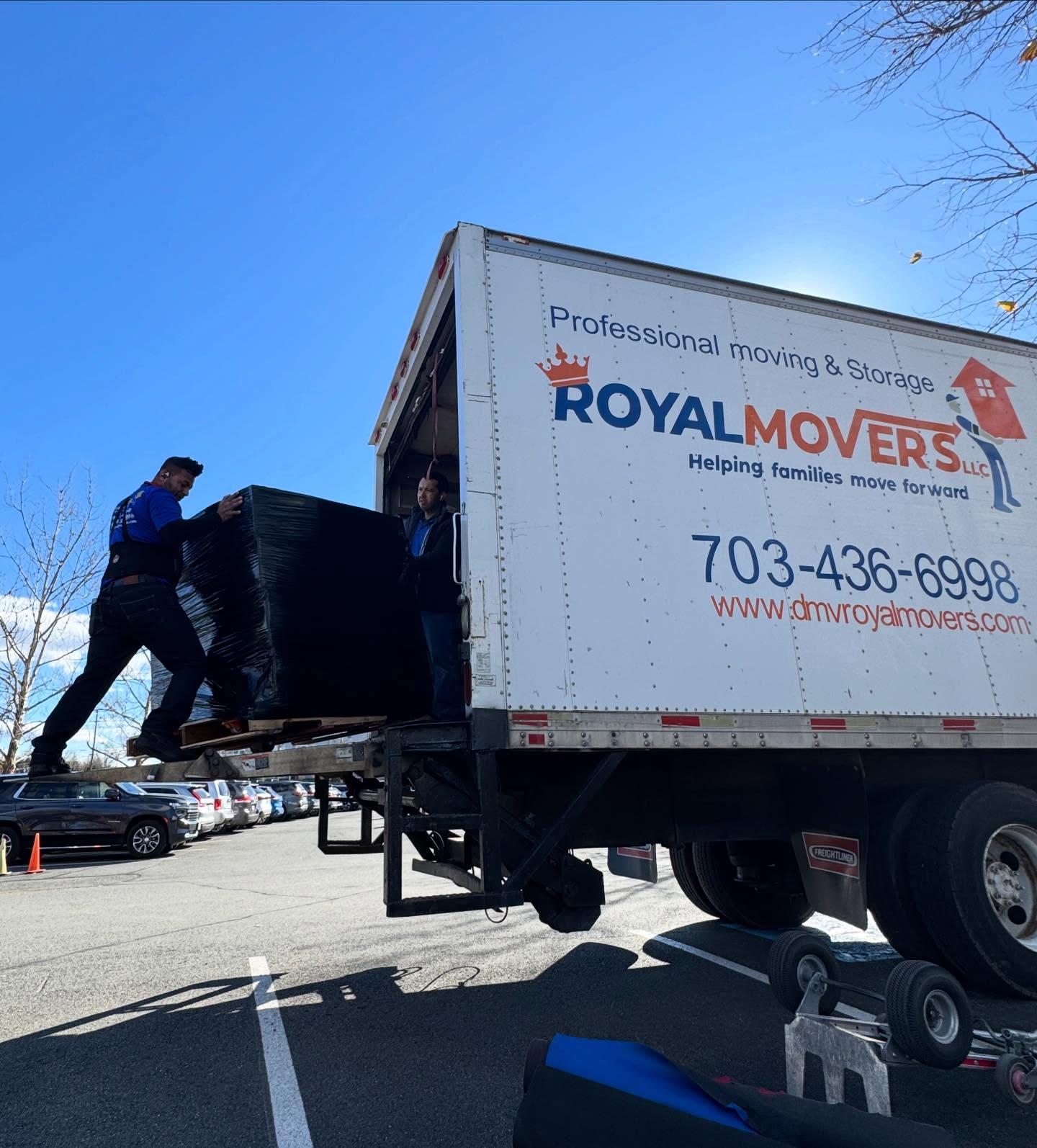 Moving truck with two people unloading pallet of food boxes