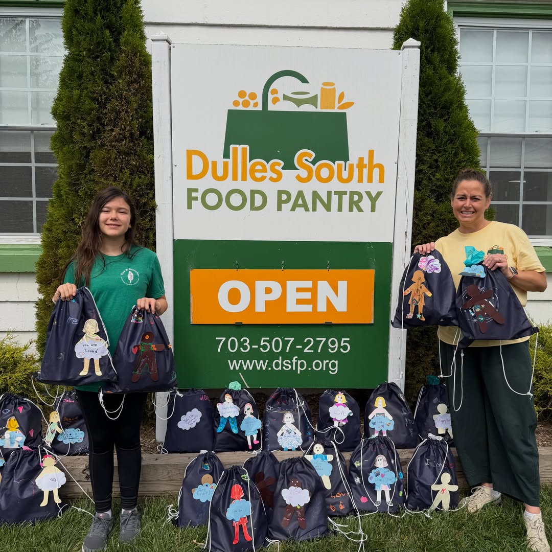 Two people standing next to Pantry sign outside with decorated birthday bags
