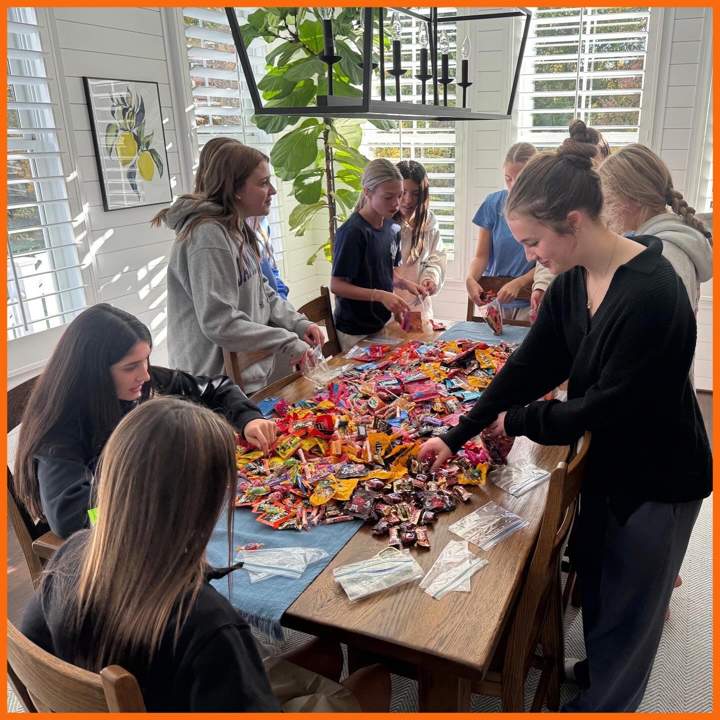 Girls standing around a table of candy filling up Halloween treat bags
