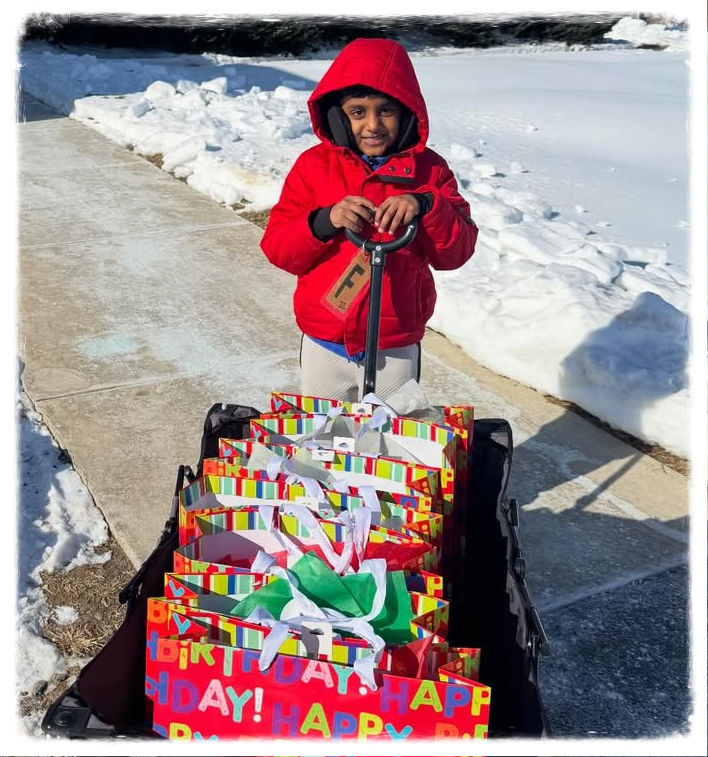 Child standing outside in the snow with wagon full of colorful birthday bags