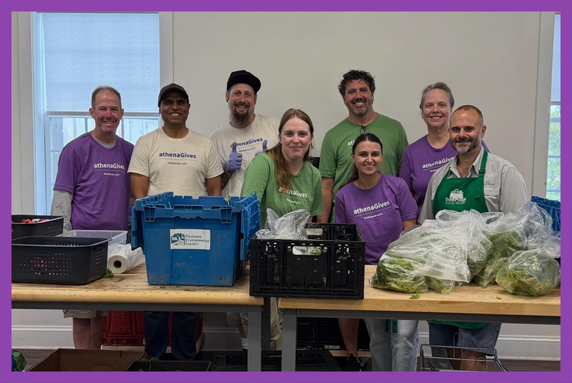 Group of volunteers posing for a photo together behind a table of fresh produce