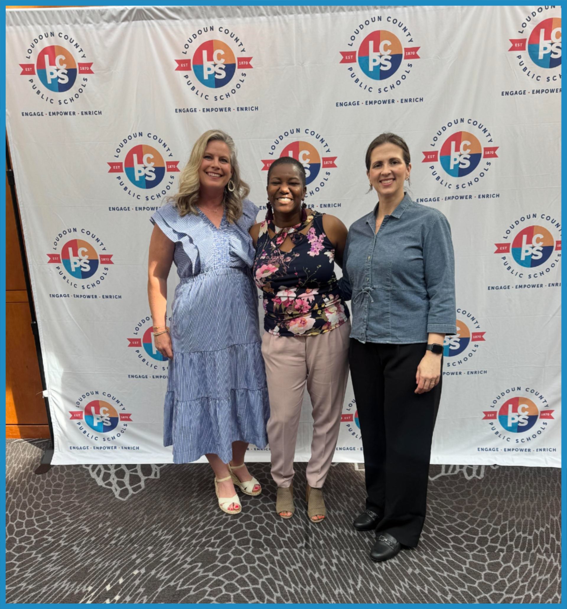 Three woman posing in front of LCPS banner