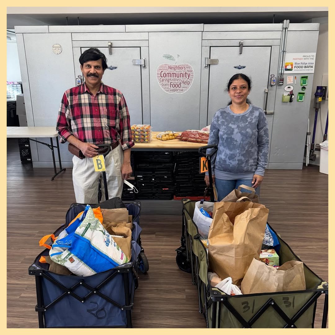 Two people standing behind wagons of food donations