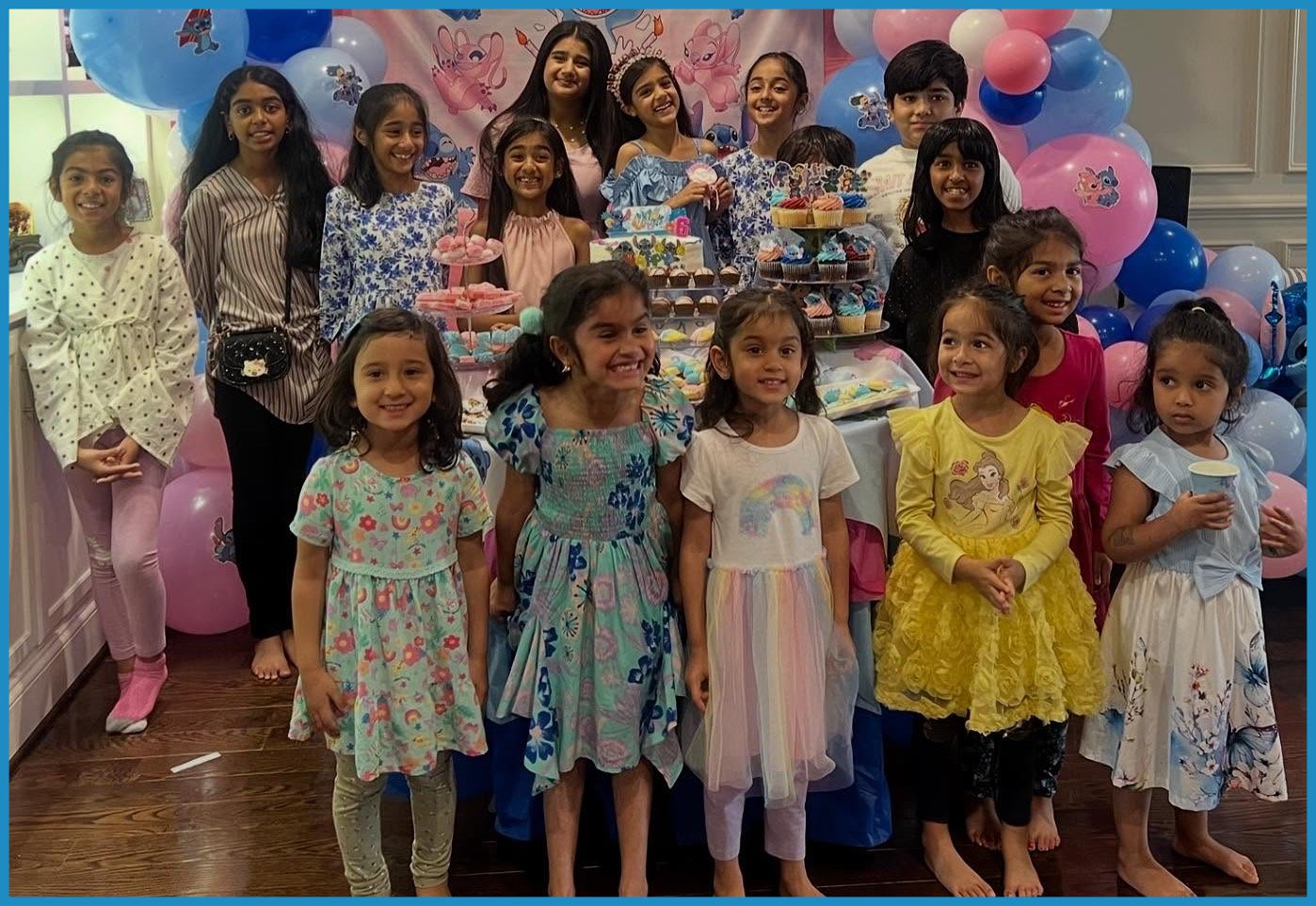 Party guests smiling for a picture around cupcakes and balloons