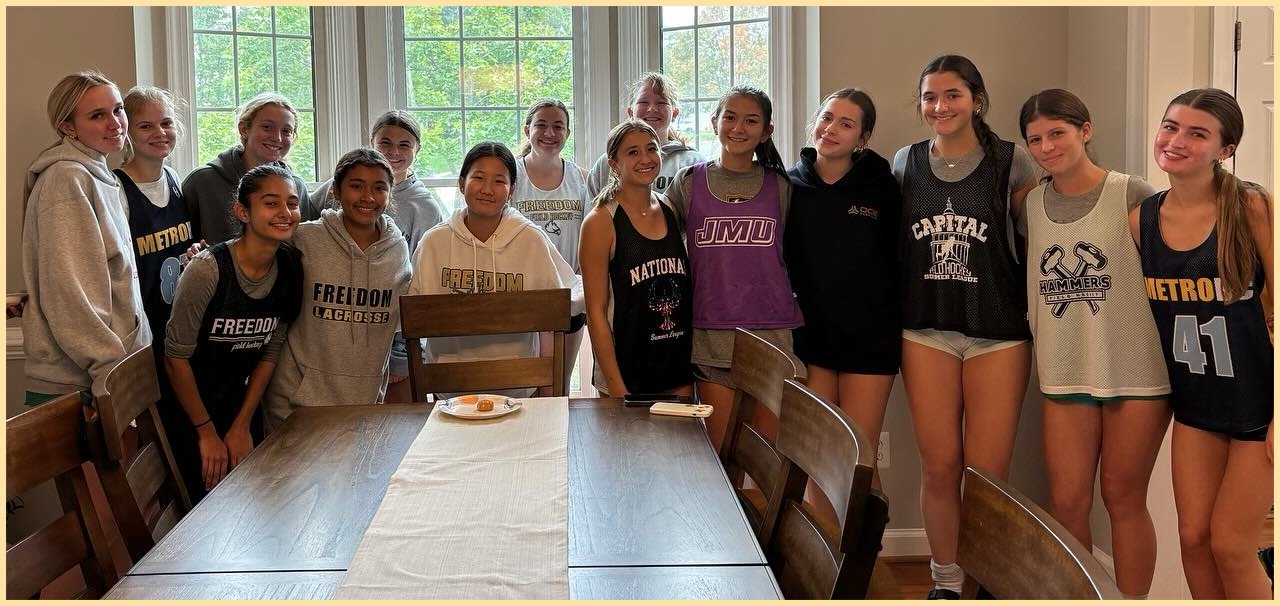 Field hockey team members posing for group picture in front of a window