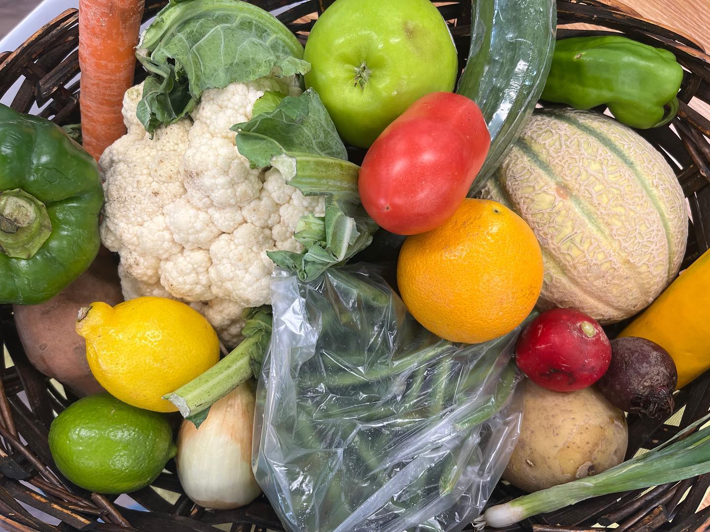 Image of fresh produce, including tomatoes, cantaloupe, cauliflower, peppers, green beans, lemon, lime, carrot, potato