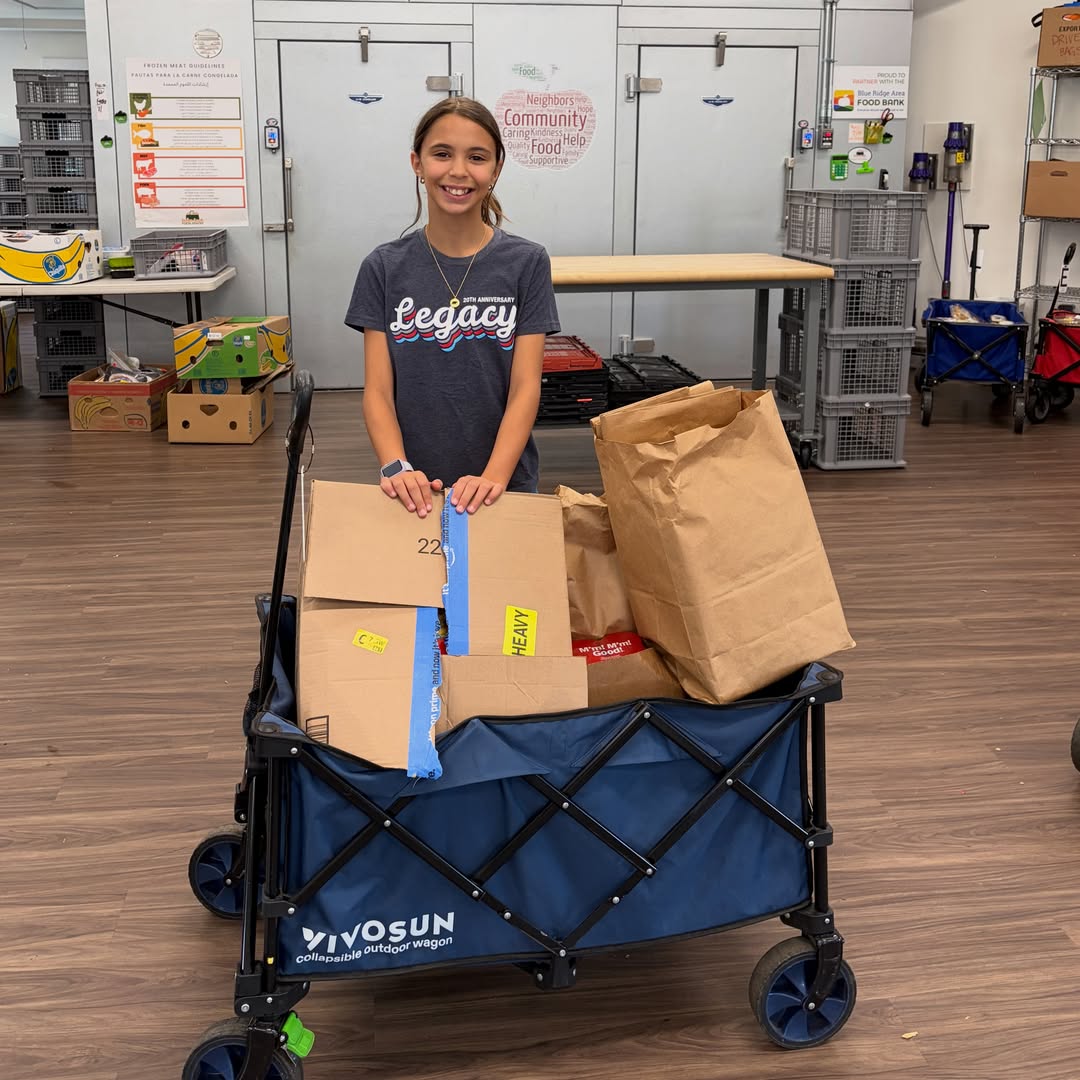 Girl standing inside the Pantry with wagon full of donations