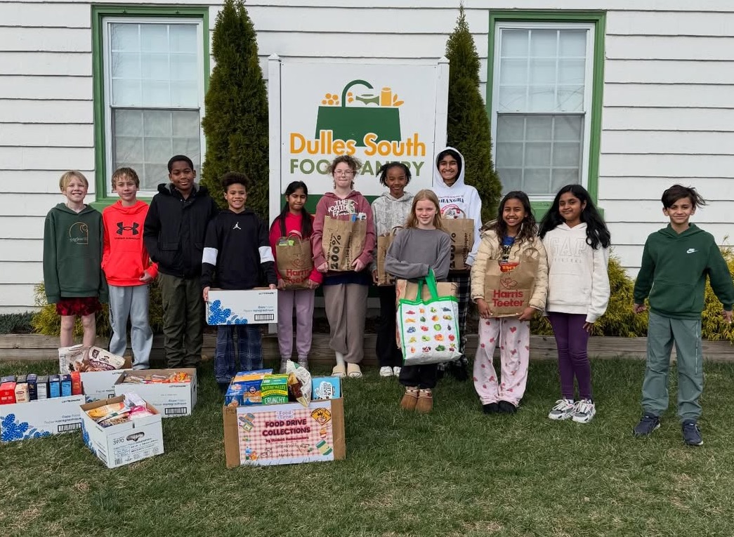 Twelve elementary school students standing in front of the DSFP sign with donated food