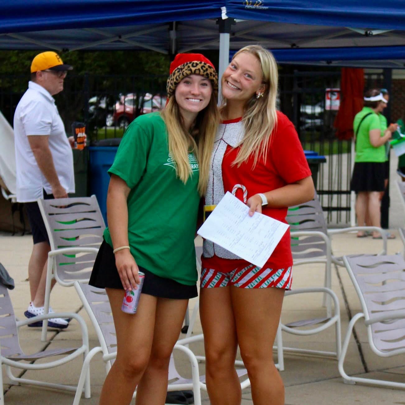 Two people standing on a pool deck dressed in Christmas themed clothing