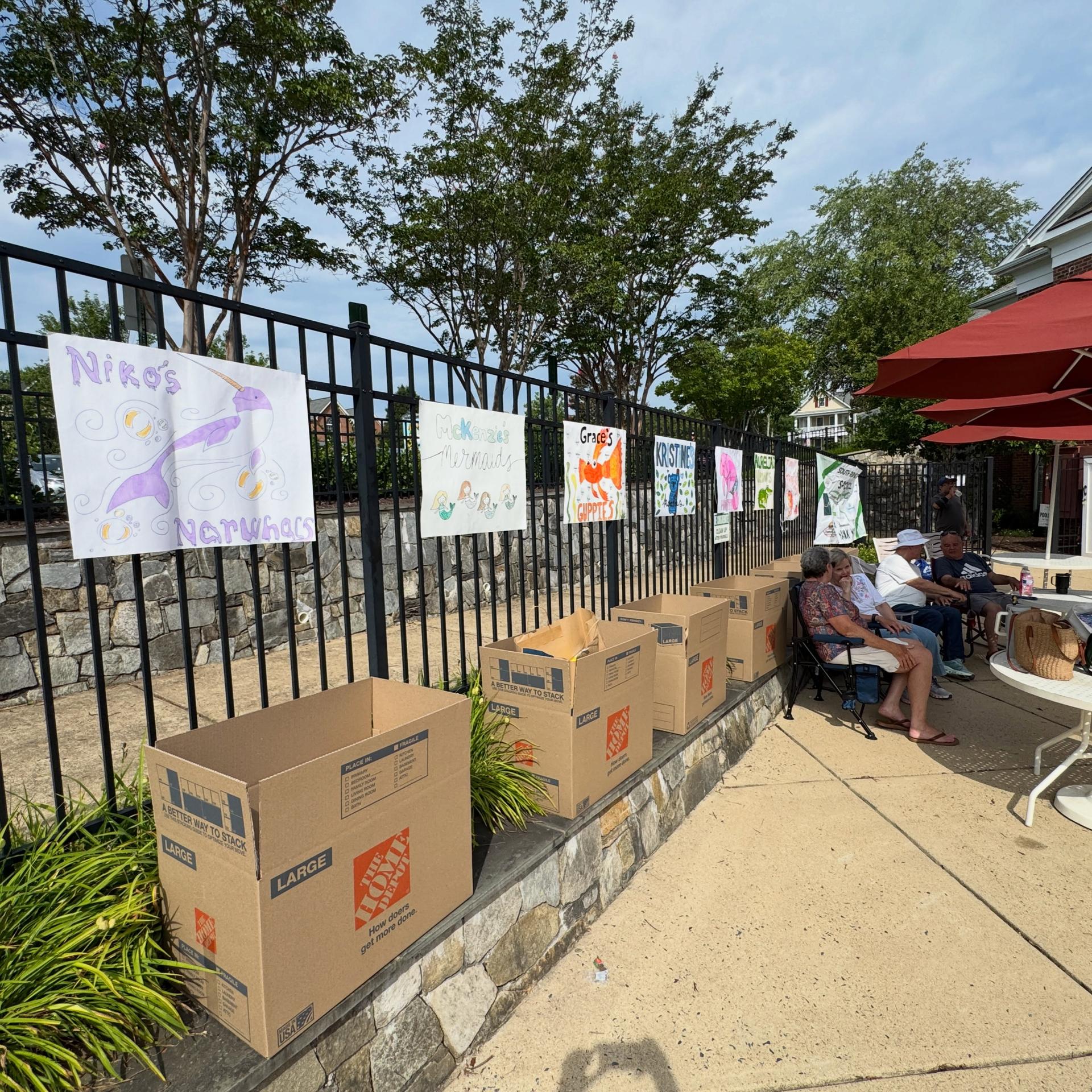 Picture of boxes to collect donations with decorated posters hanging on the fence