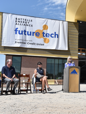 Representative Wendy Horman of the Idaho State Legislature stands at a podium in front of the partially constructed Future Tech Building. A large banner on the building reads “Battelle Energy Alliance (BEA) Future Tech Building in partnership with Frontier Credit Union.”