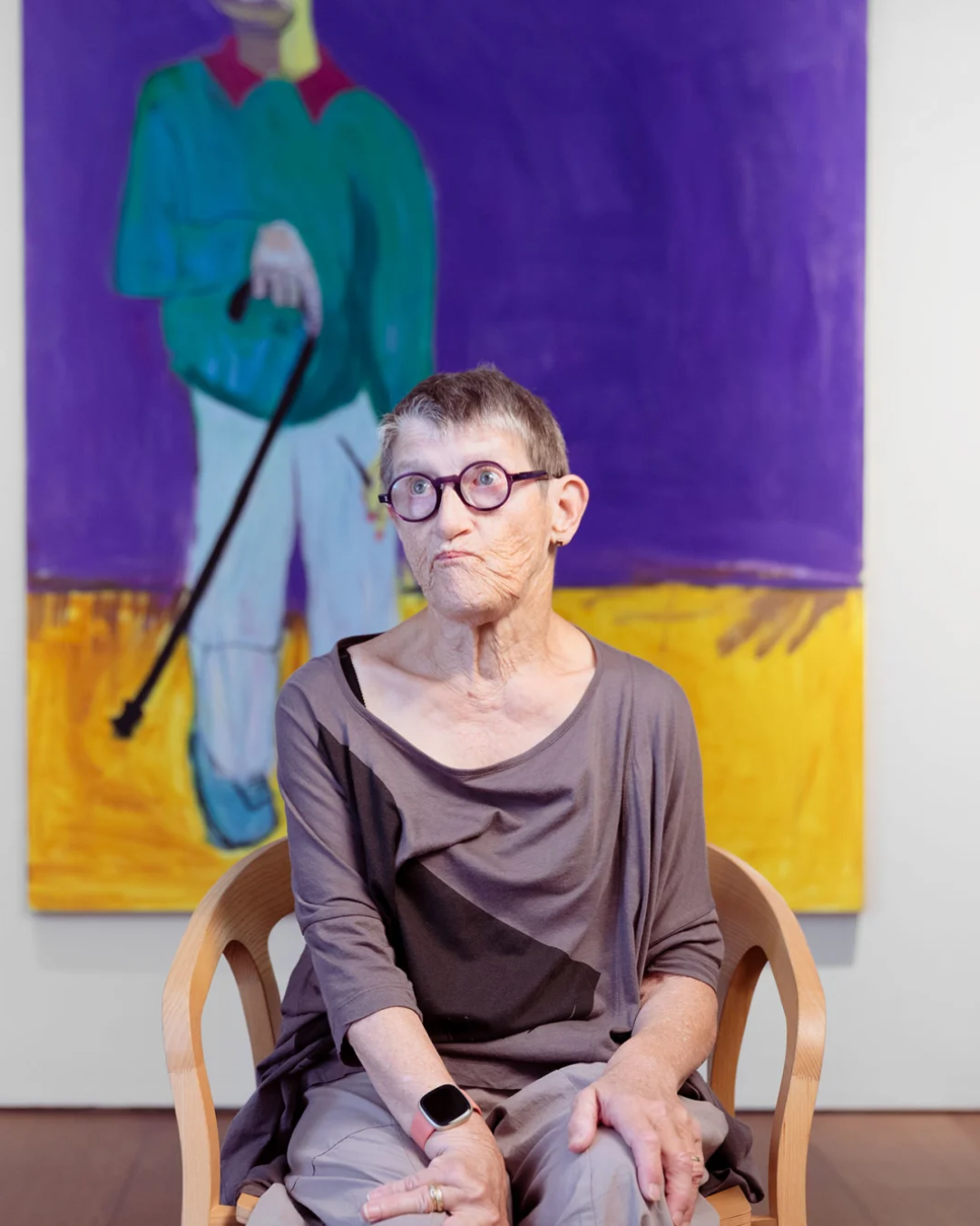 Artist Lucy Jones sits in front of one of her self portraits