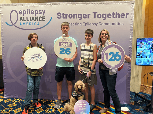 One adult and 3 kids and a dog, all holding signs of epilepsy support.