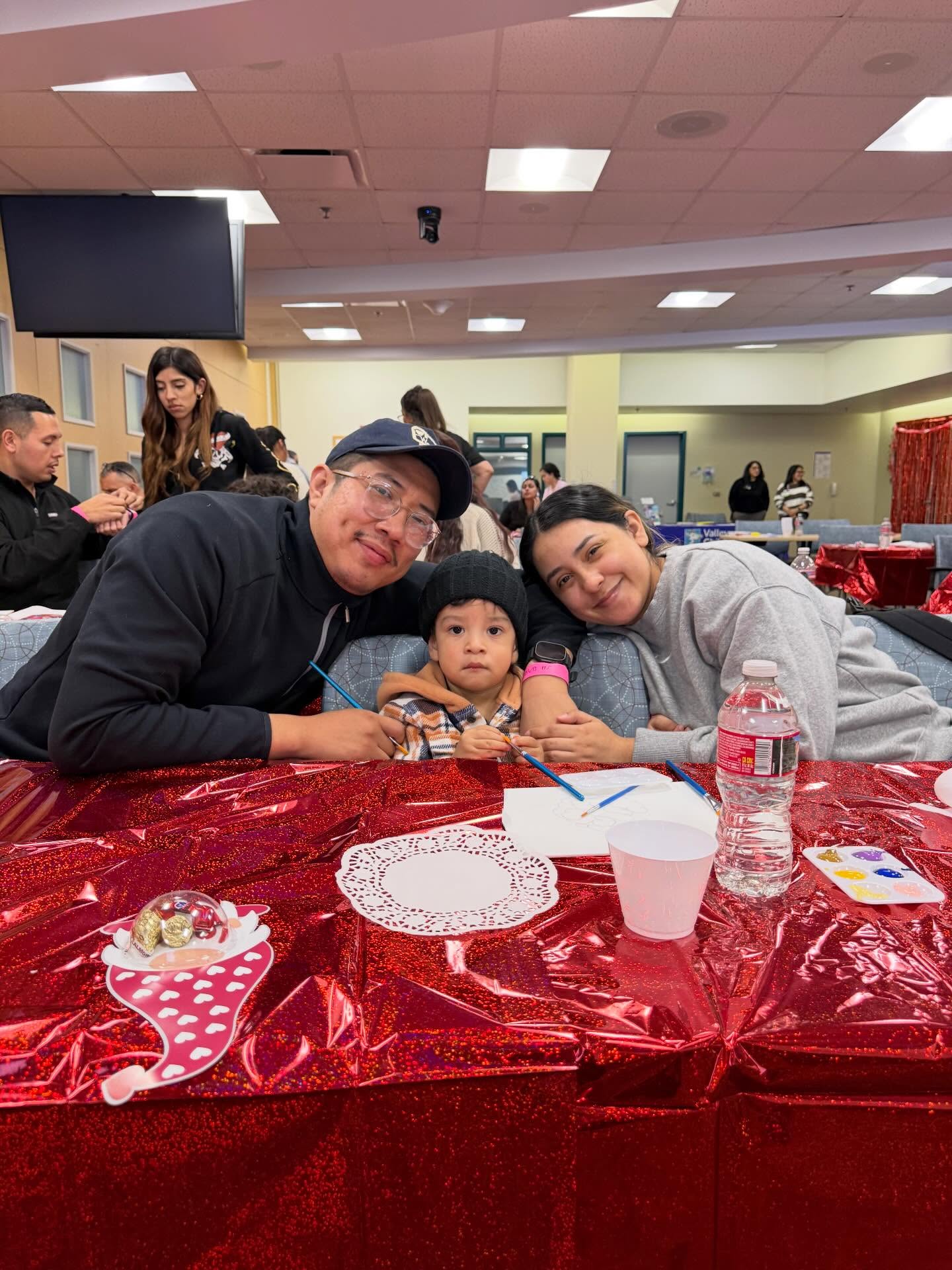 Smiling family of three at a valentines day themed paint night