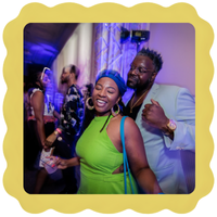 A woman in a bright green dress and a man in a light suit smile and pose together at a lively indoor event, with other people mingling in the colorful background. The image has a yellow scalloped border.