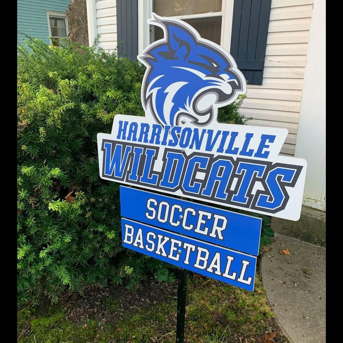 Wildcat yards sign with soccer and basketball plaques in a front yard