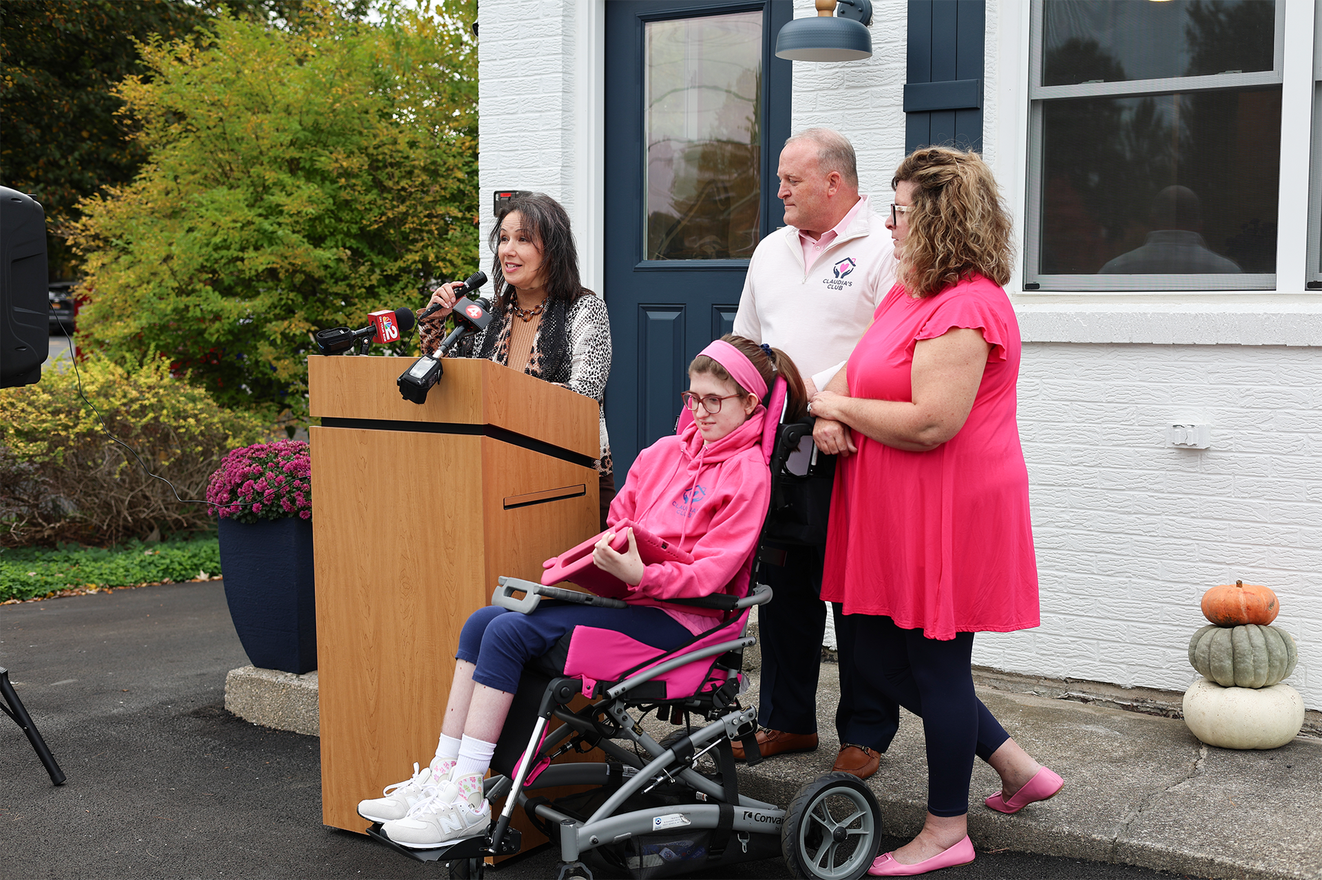 Lisa Foti, CEO of The Summit Center, speaks at a podium beside Tom Rosenecker, president of Claudia's Club, his wife, Mary, and their daughter, Claudia.