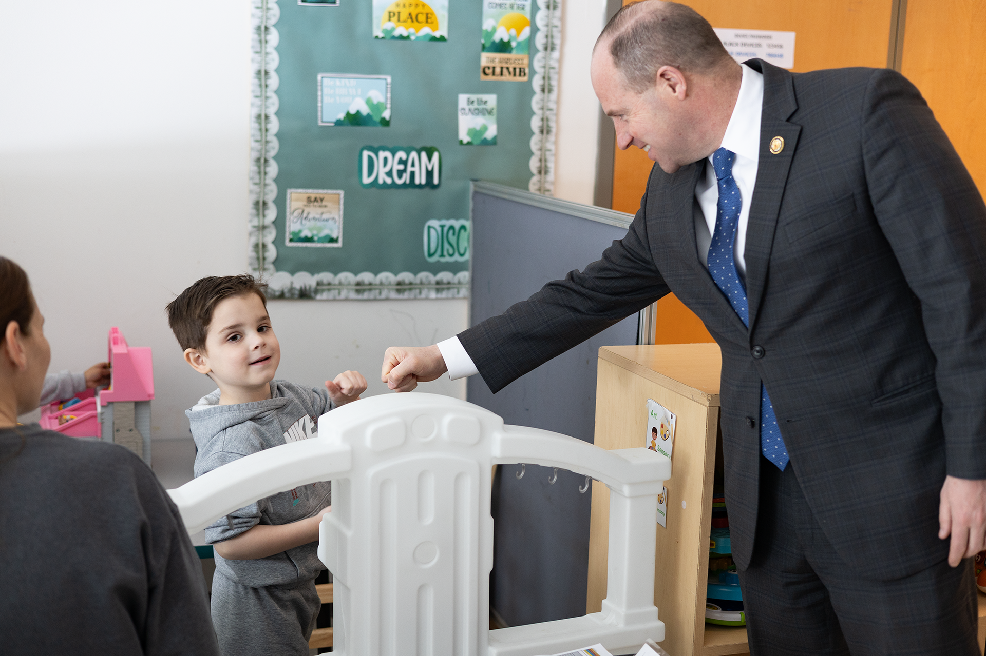 A young boy in a gray sweatshirt fist bumps Rep. Tim Kennedy