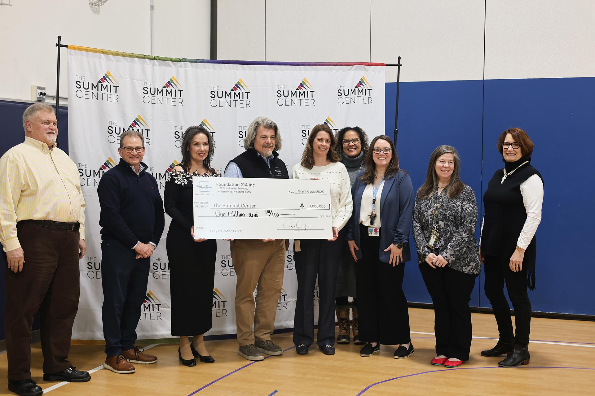 A group of professionals pose with a big check for $1 million dollars in a gymnasium.
