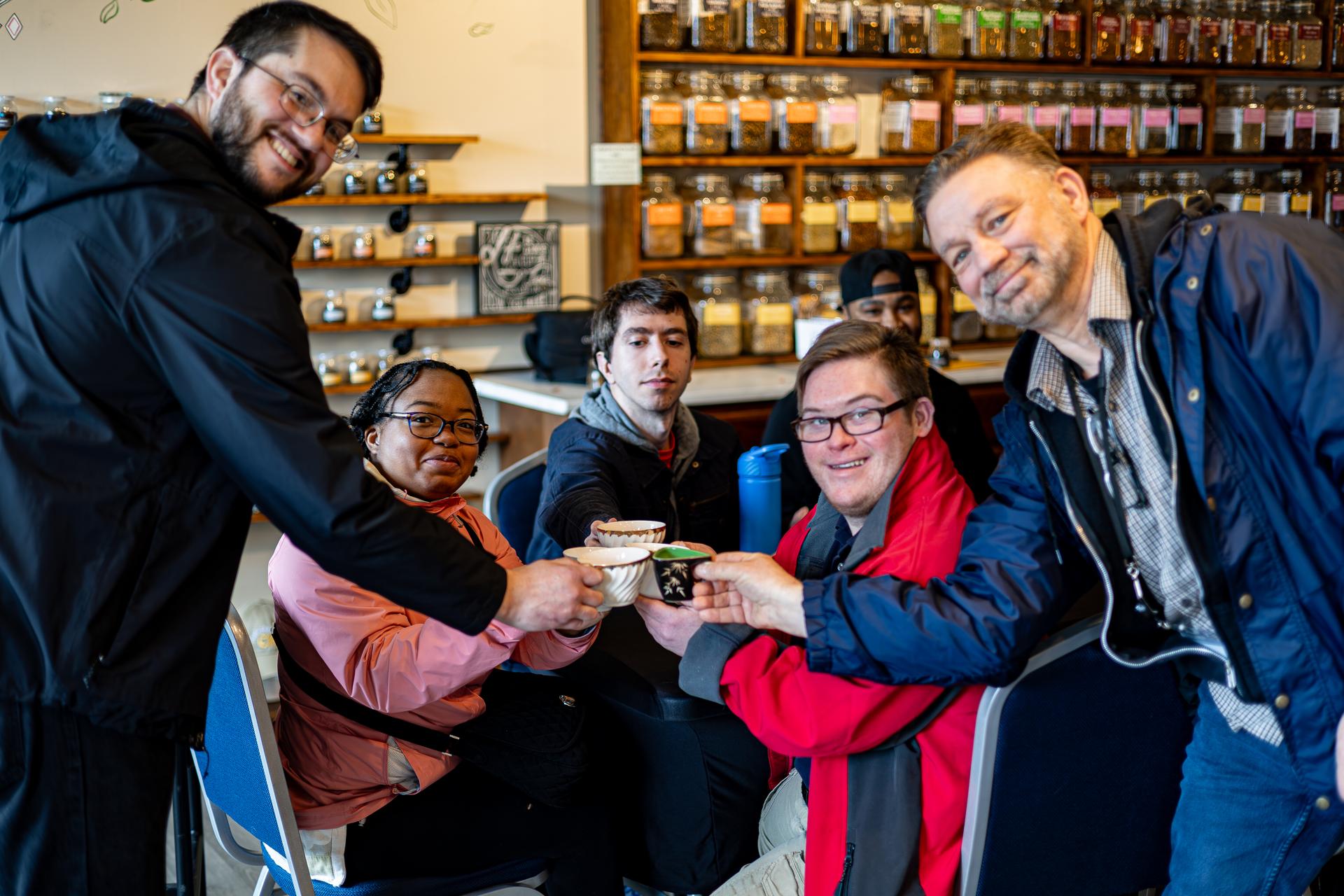 A group of people cheers with their cups of tea.