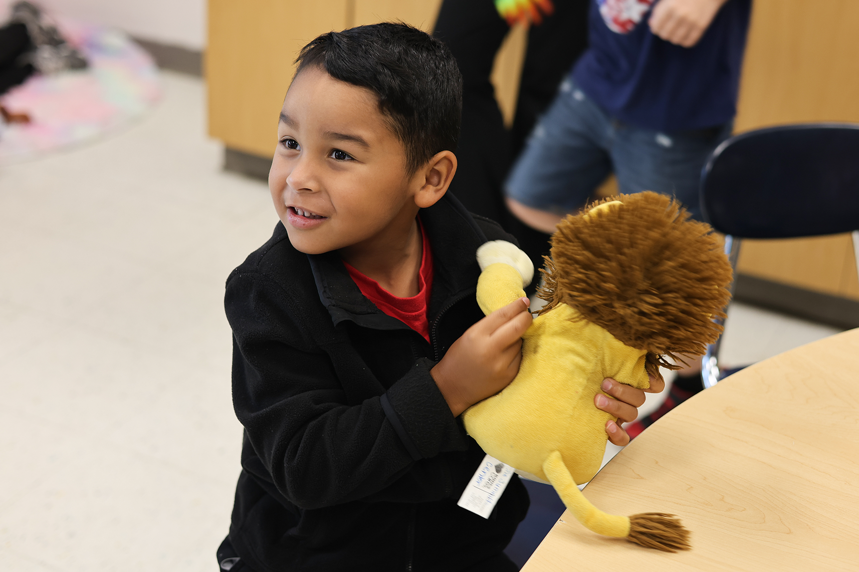 A young boy holding a lion stuffed animal smiles