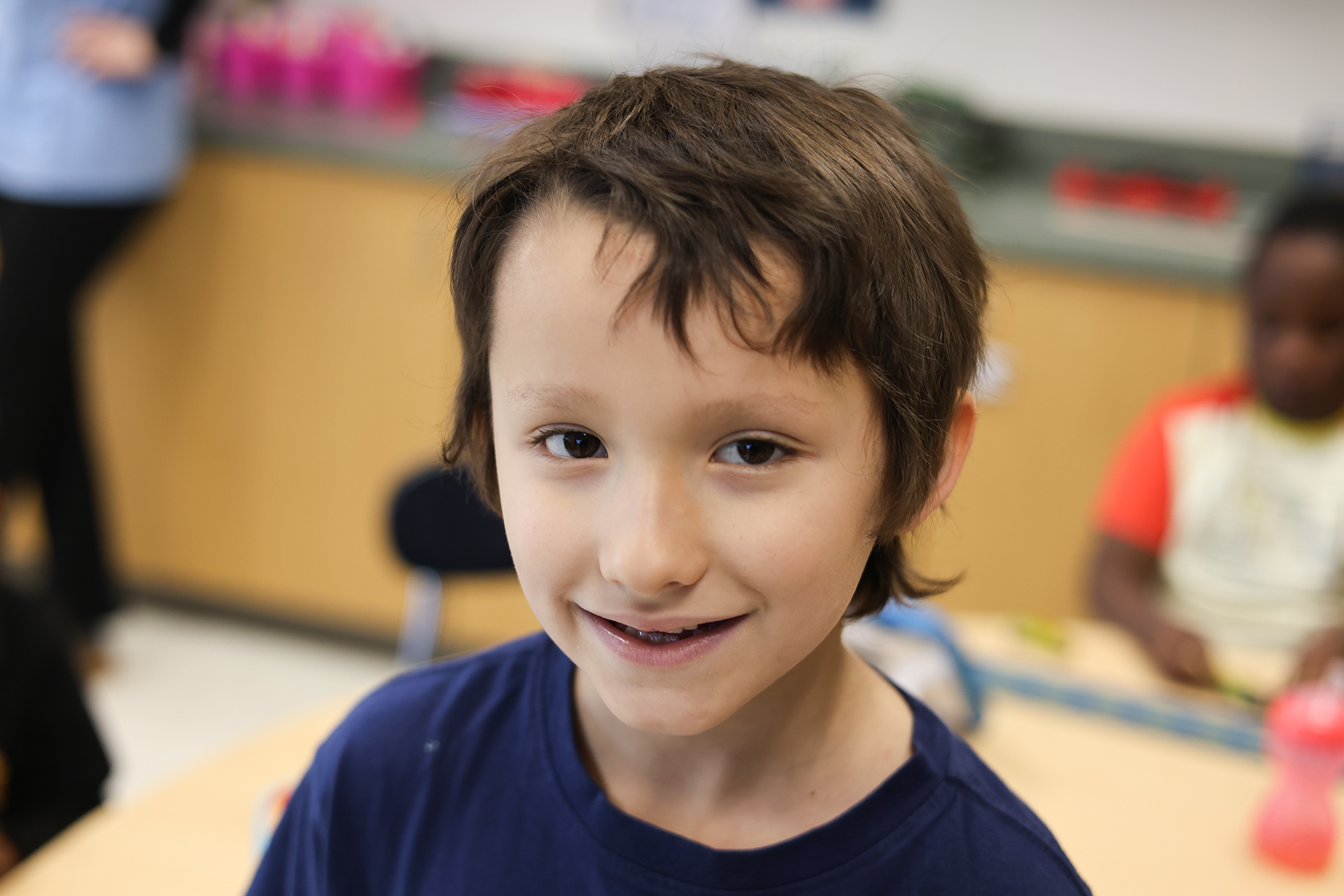 A young boy in a blue shirt smiles
