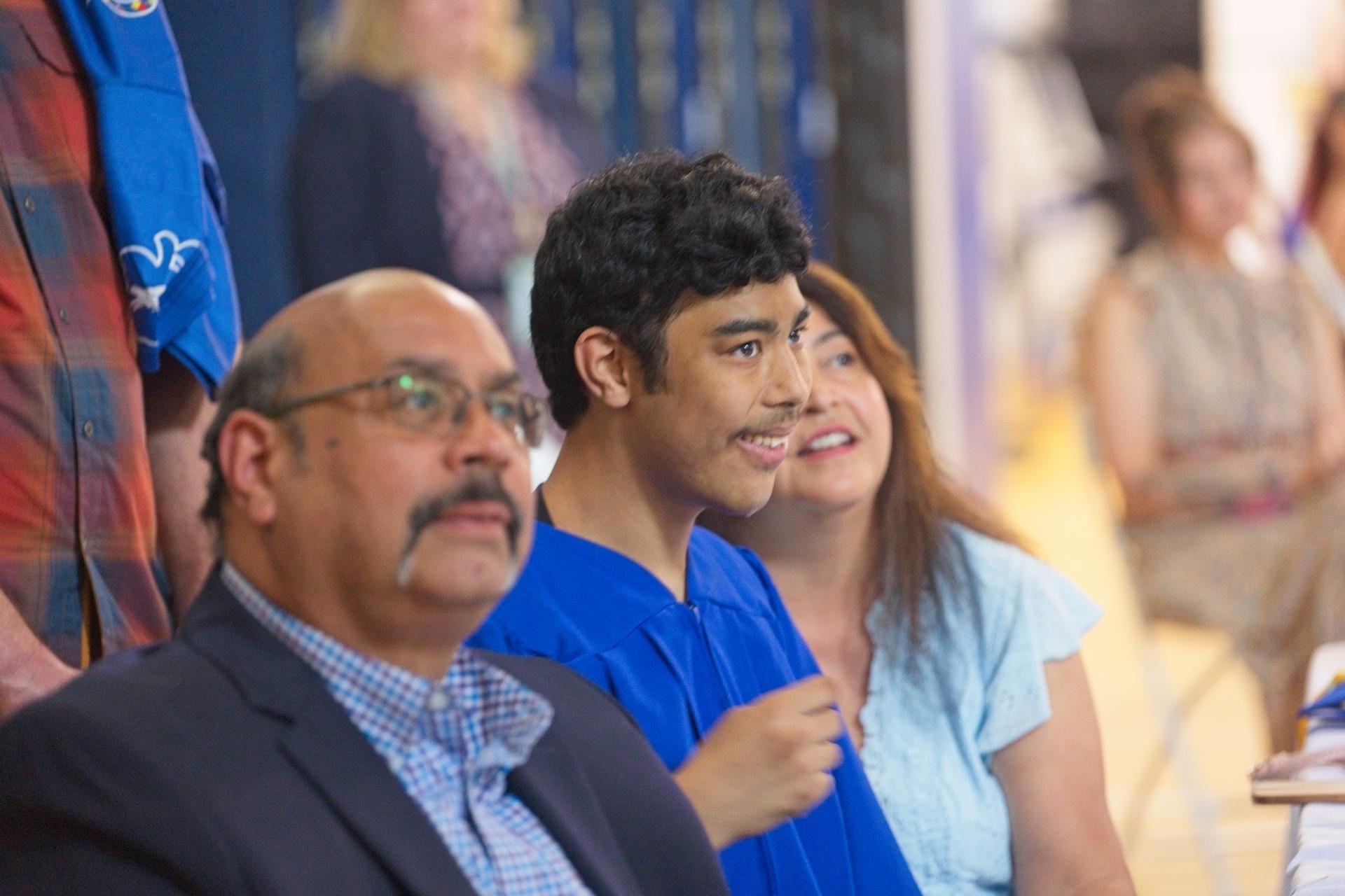 A young male graduate sits next to his father during graduation.