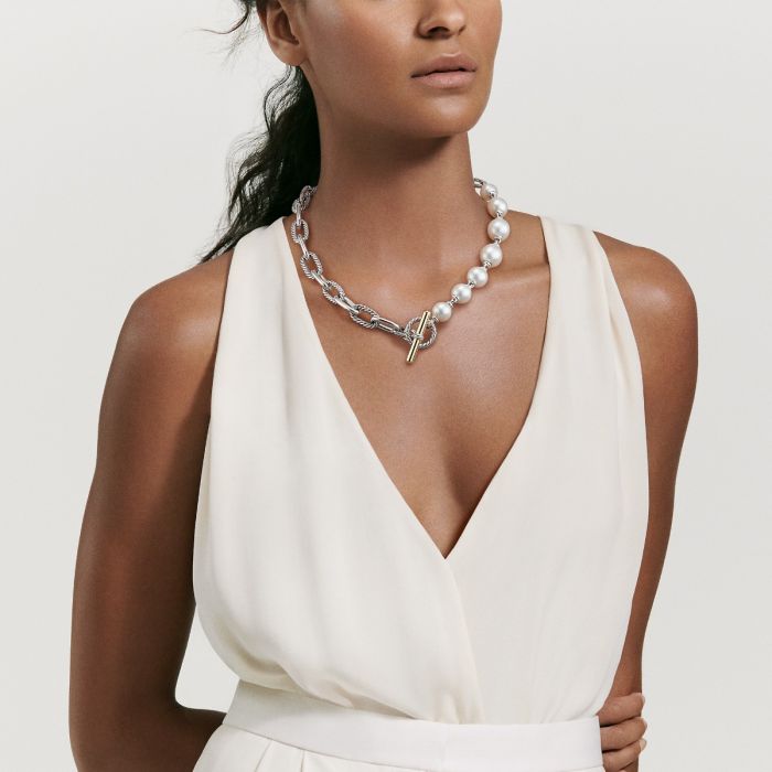 A woman in a white dress wears a silver necklace with pearls.