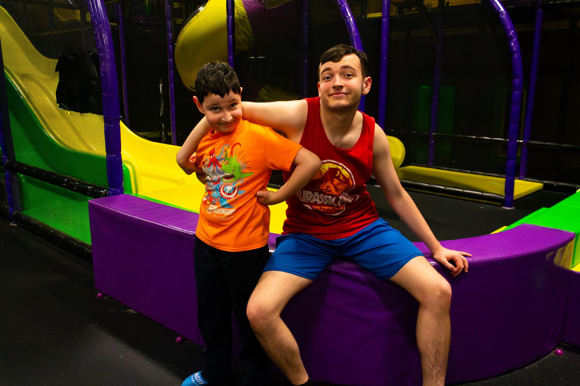 Two young boys sit near a slide and smile for the camera.