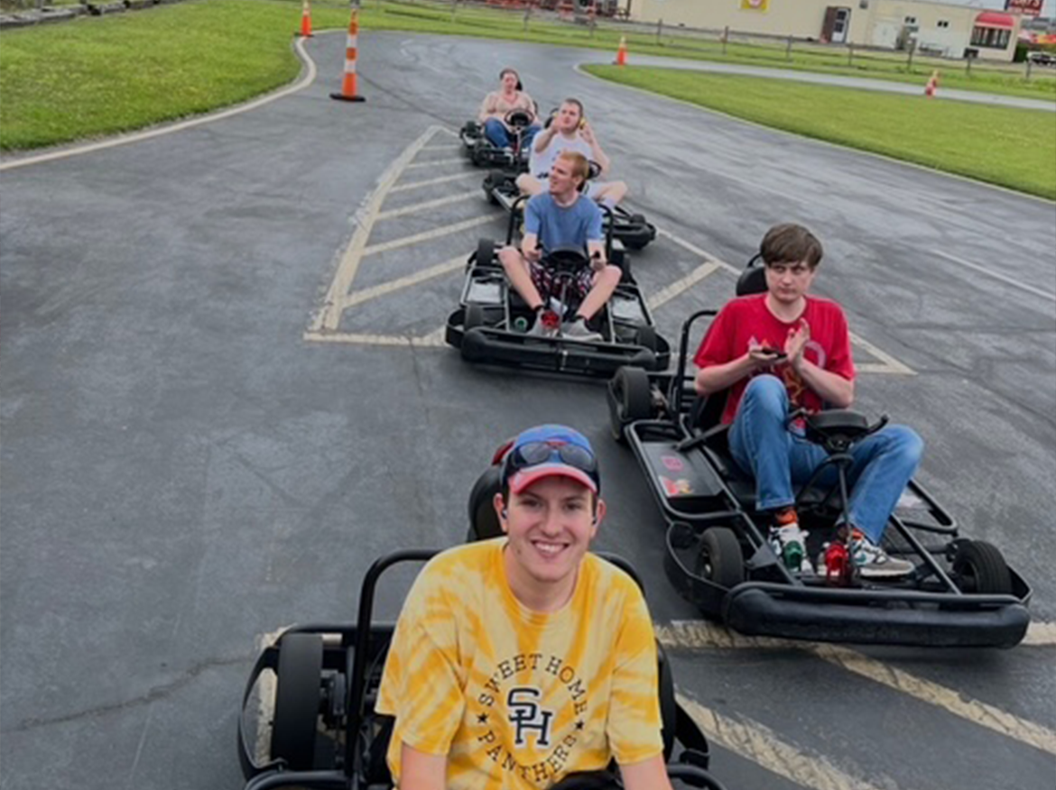 A group of people sit in go karts waiting to start driving.