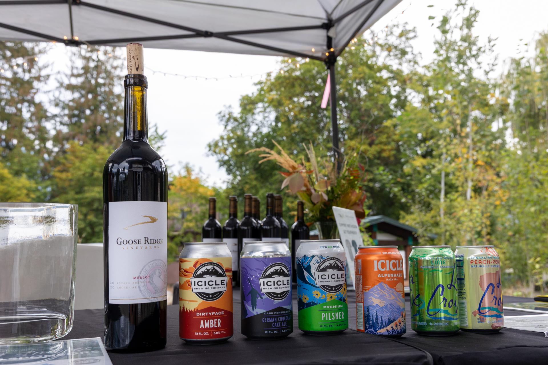 A picture of canned Icicle Brewing beer, cans of sparkling water, and a red wine from Goose Ridge. 