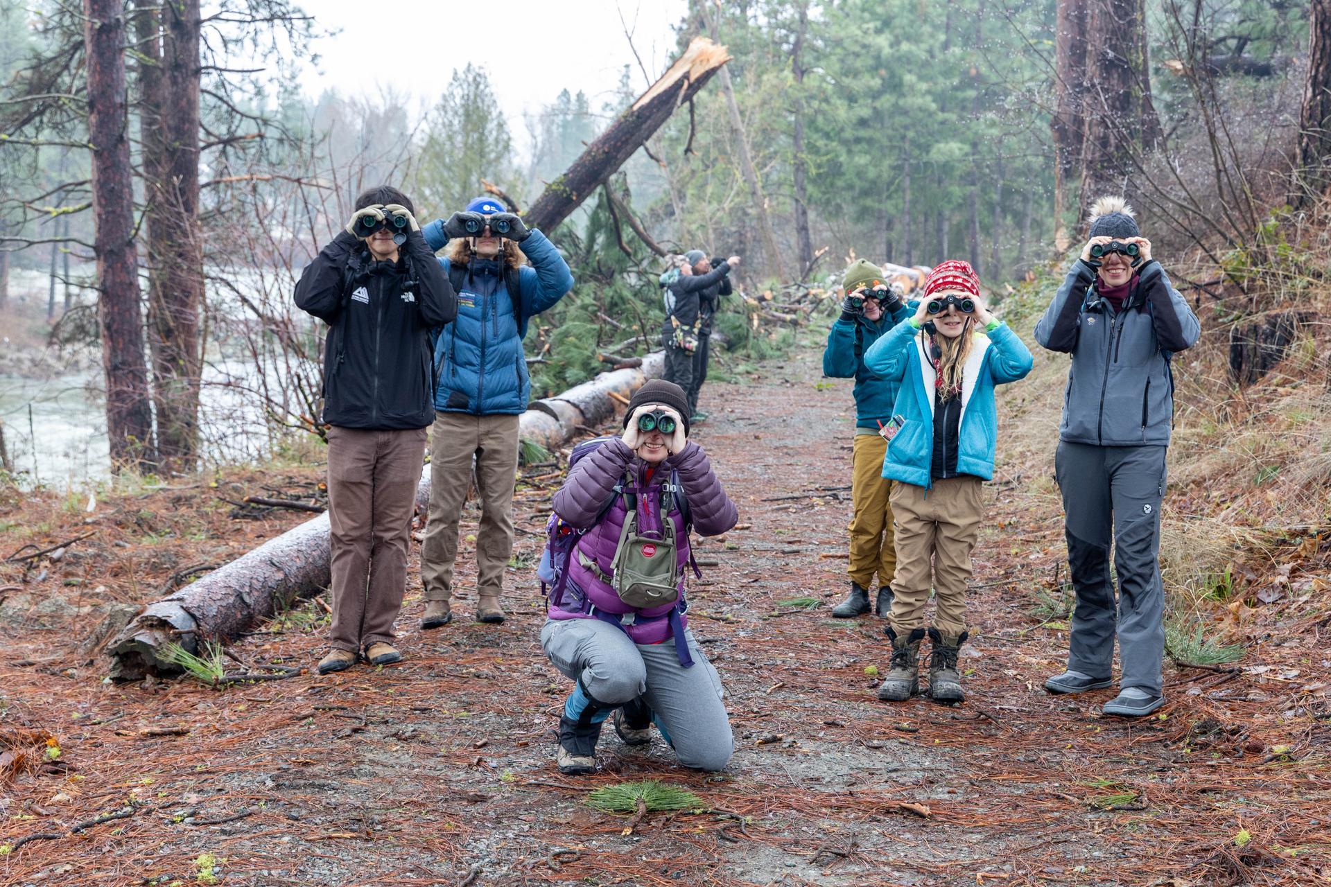 A picture of birders looking through binoculars at the camera.