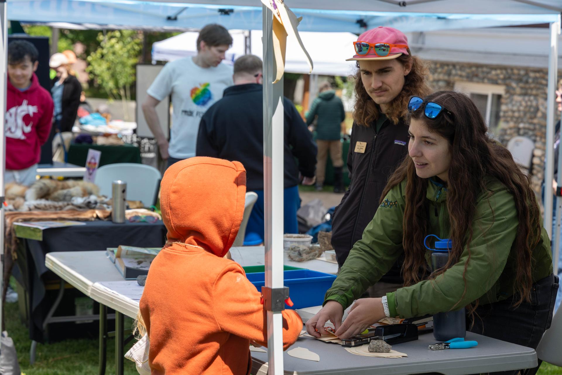 WRI Educators assisting a child with an educational activity during Bird Fest Community Fair.