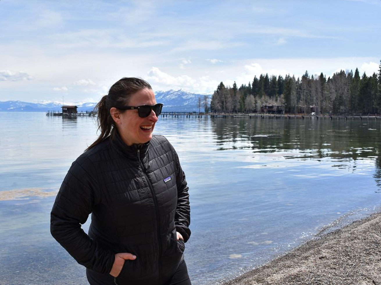 Image of Cristina Barone standing on a beach with water and mountains in the background.