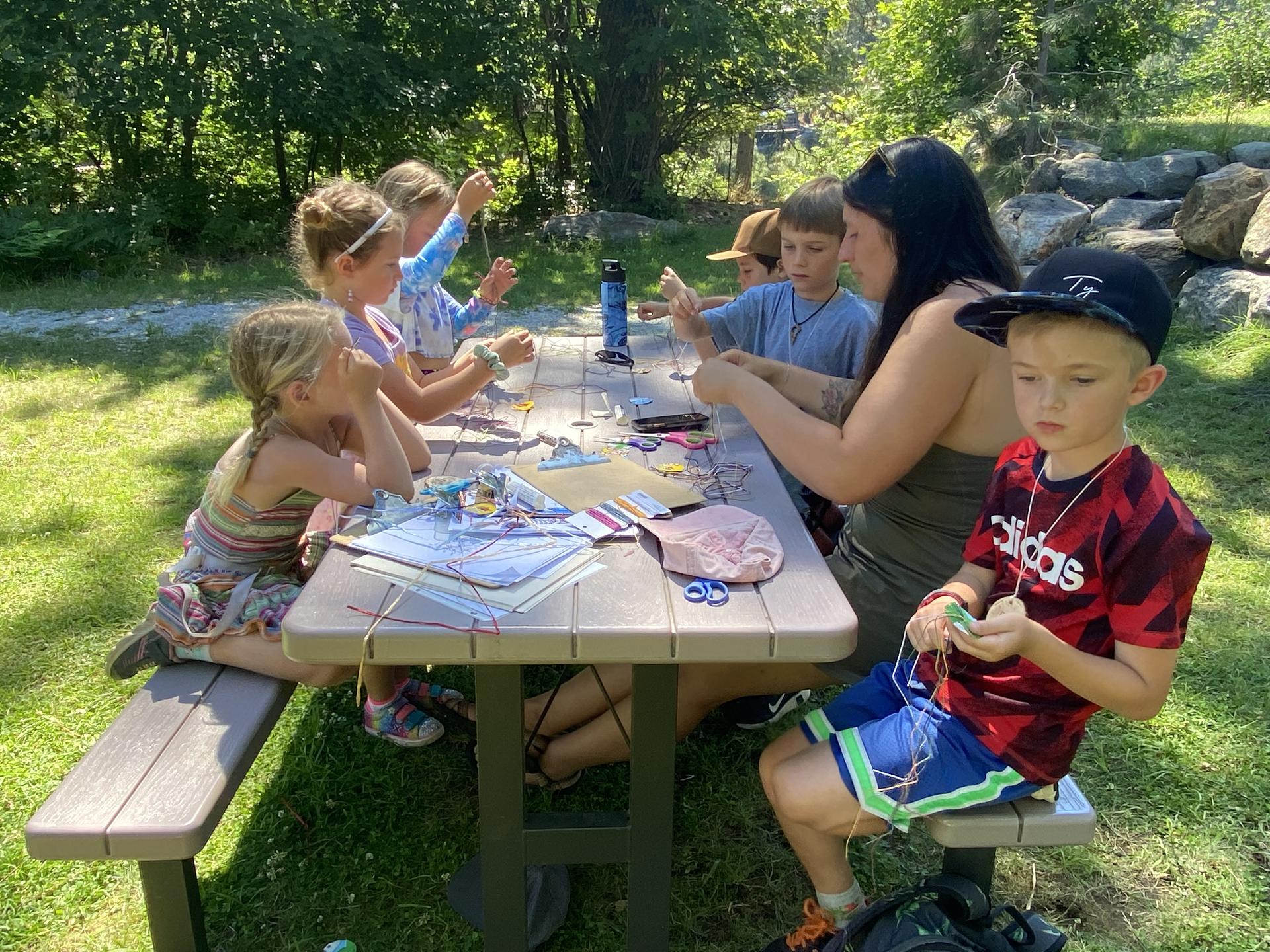 A photo of Intern Hannah making bracelets with the WRI Summer Camp.