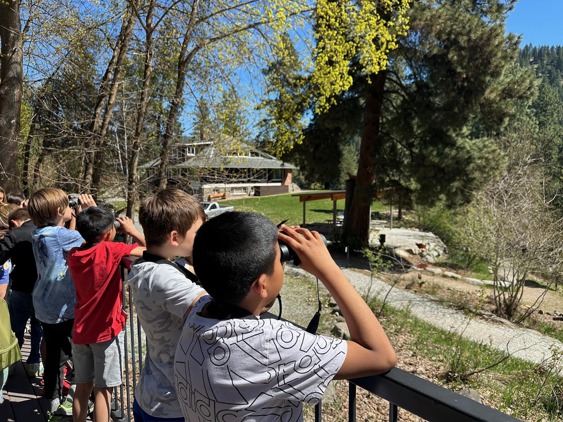 Kids running in a line with binoculars searching for birds.