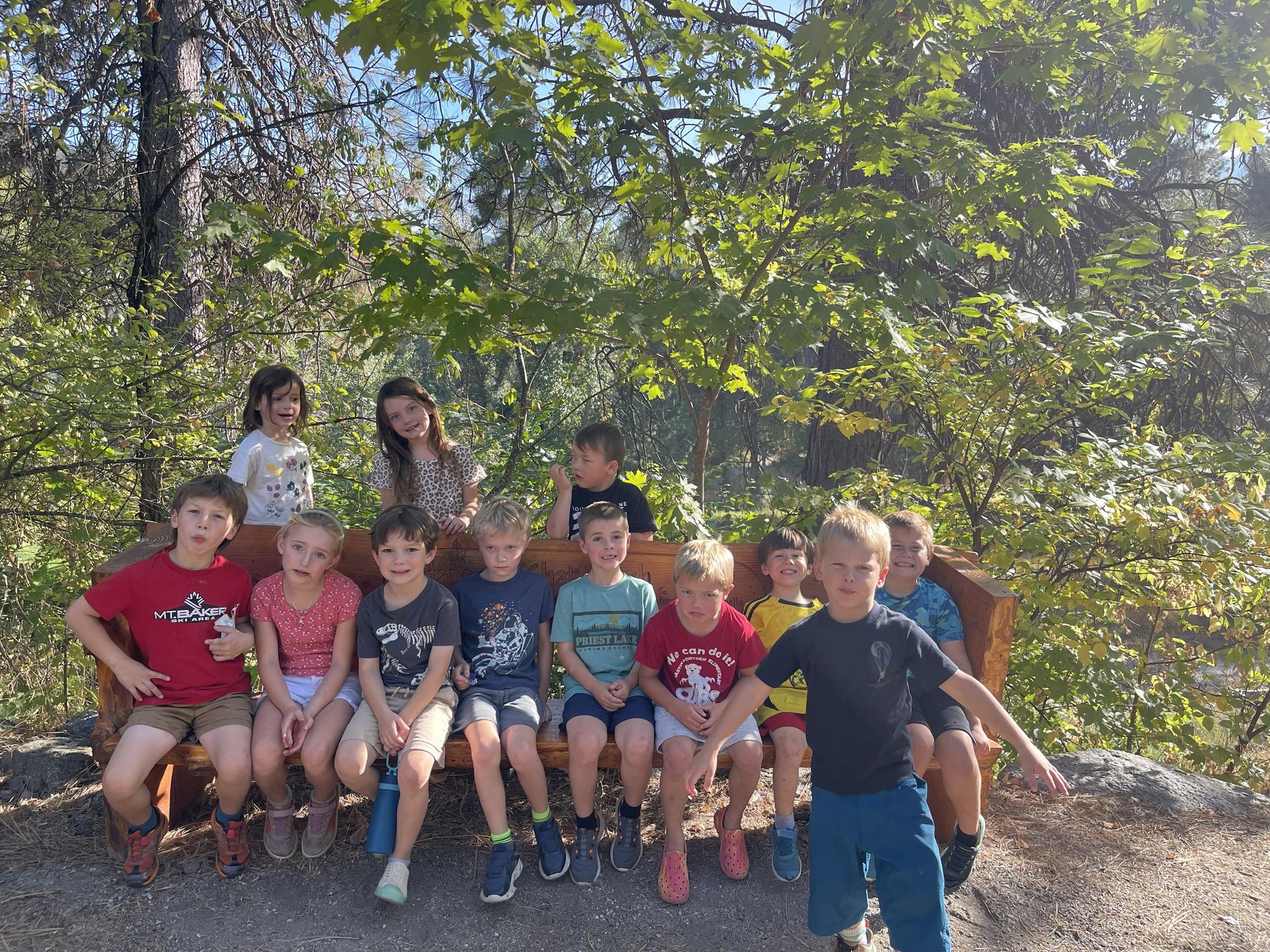 WRI After School Program students sitting on a bench outside the Red Barn.