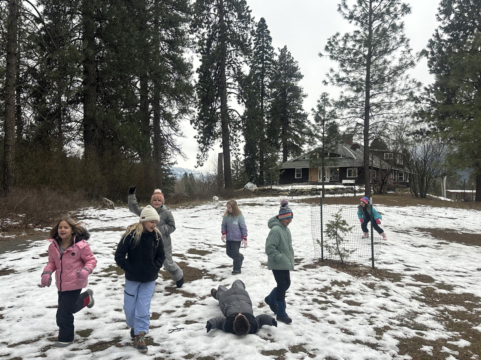 An image from WRI Winter Field Day: 4th graders playing in patches of snow on the WRI campus.