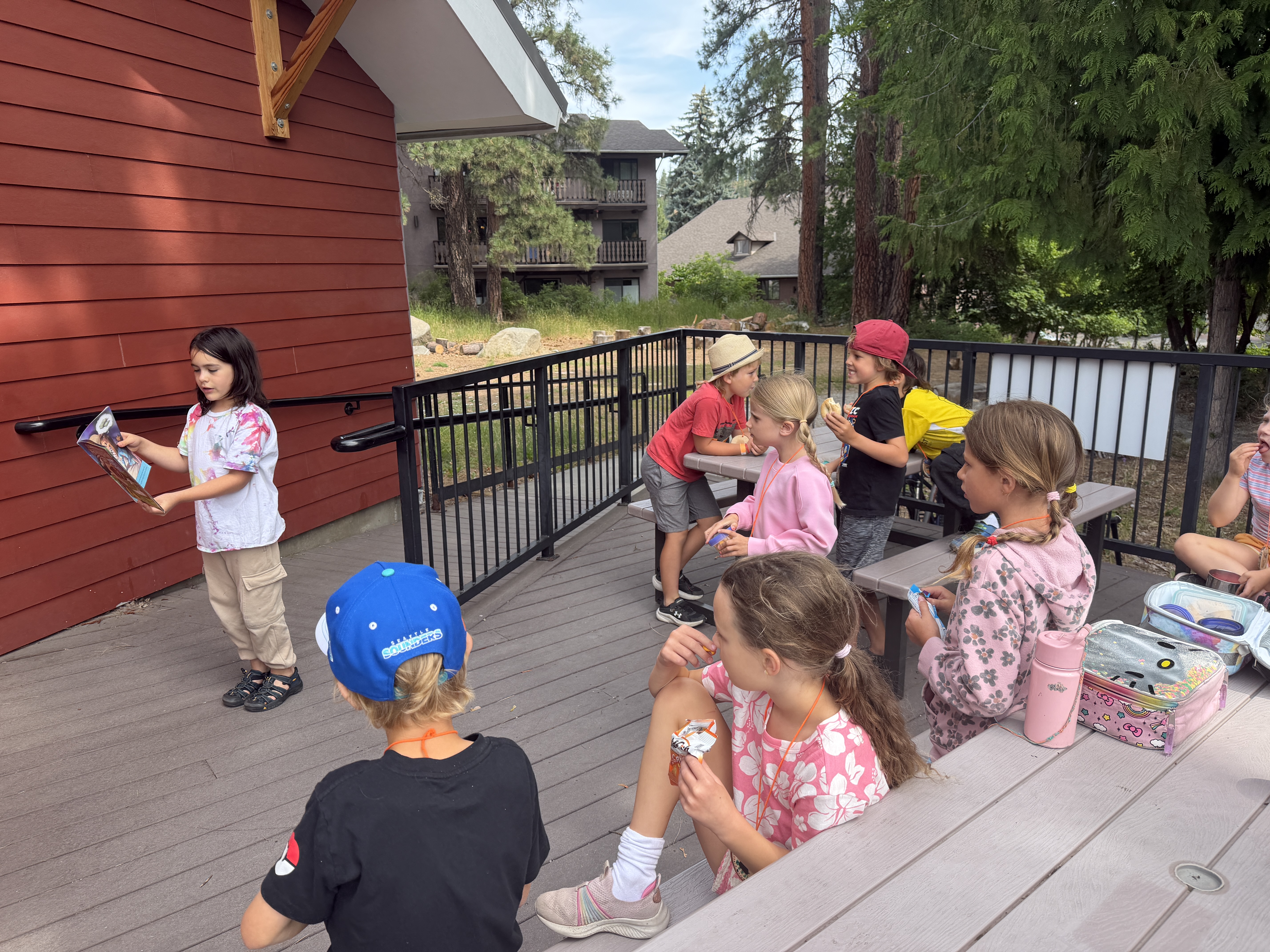 WRI Summer Camp participant reading to the other kids outside of the Red Barn.