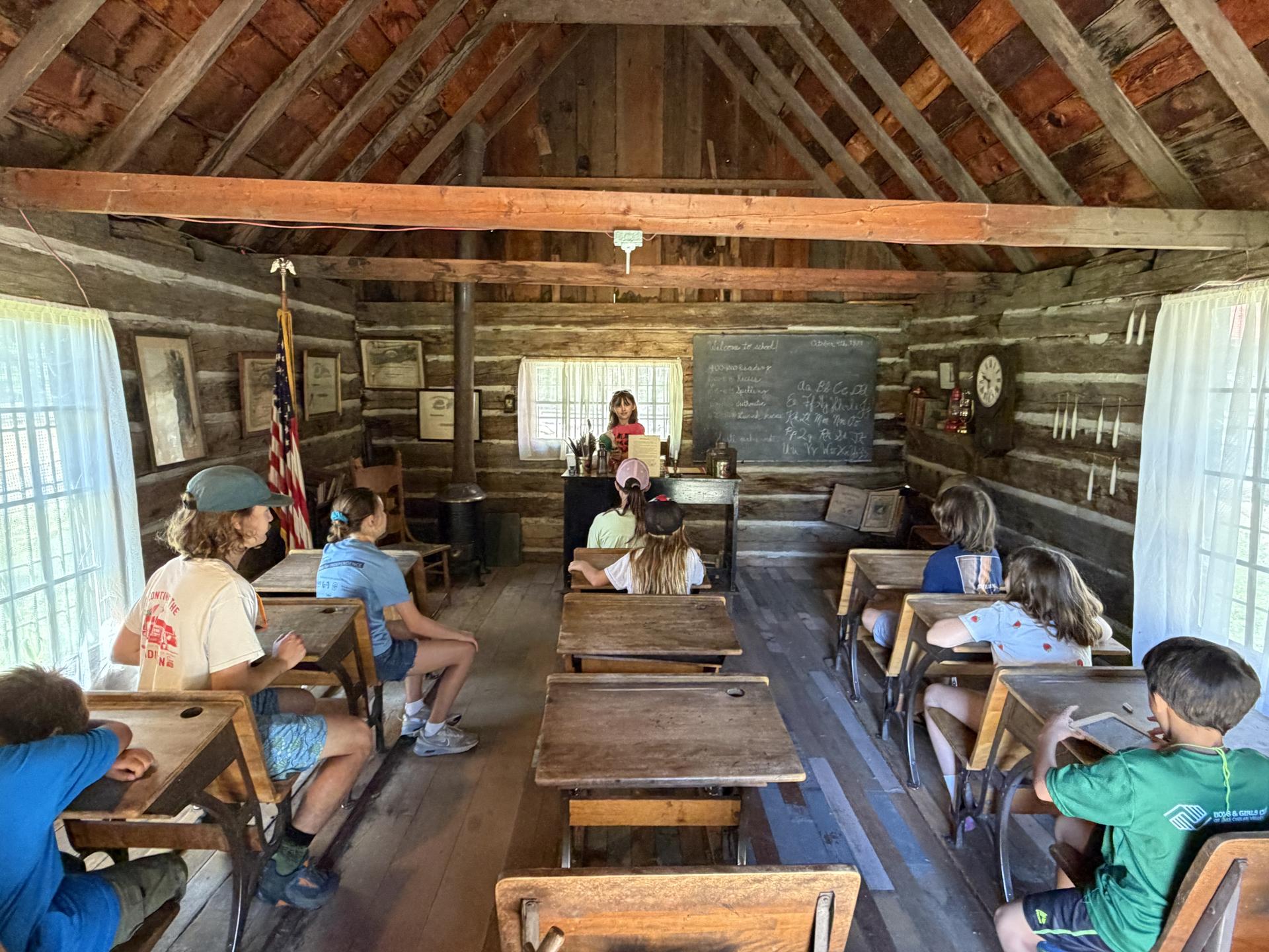 WRI summer camp students at the Cashmere Museum sitting at an old schoolhouse room with desks.